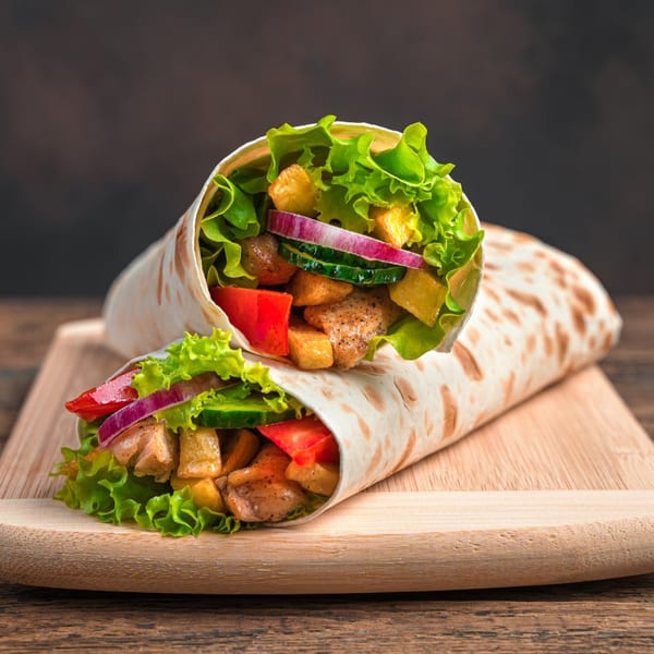 Two Pruzzo's deli wraps filled with chicken, lettuce, red onion, cucumber, and bell peppers.